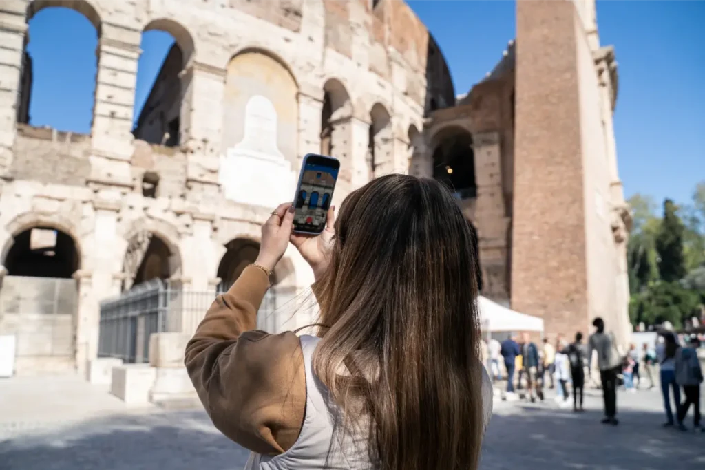 Tourist taking a photo of the Colosseum in Rome with a smartphone